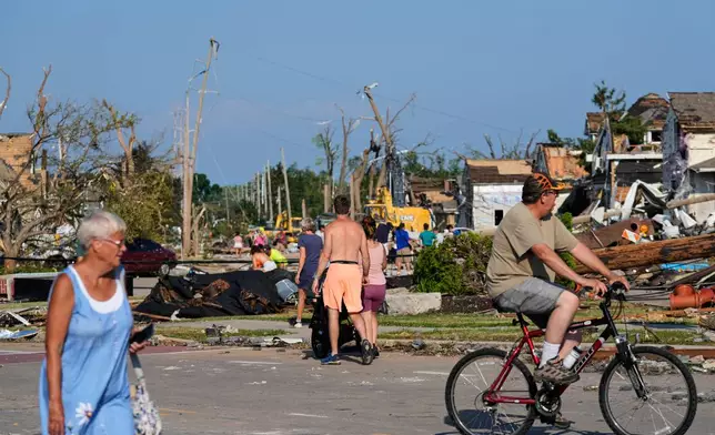 People walk among debris after a tornado struck Monday, July 27, 2026, in Menasha, Wis. (AP Photo/Kayla Wolf)