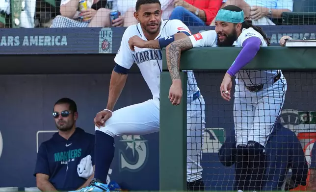 Seattle Mariners designated hitter Julio Rodríguez and J.P. Crawford talk at the dugout railing during the second inning of a baseball game against the San Francisco Giants, Saturday, July 18, 2026, in Seattle. (AP Photo/Lindsey Wasson)