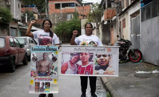 Glaucia dos Santos, left, and her sister Nadia dos Santos raise their fists and hold photos of their late sons outside Glaucia's home in the Morro do Final Feliz favela in Rio de Janeiro, Thursday, June 4, 2026. Nadia's two sons Cleyton dos Santos Bravo and Cleyverson dos Santos Bravo, and her sister's son Fabricio dos Santos, were killed by police. (AP Photo/Bruna Prado)