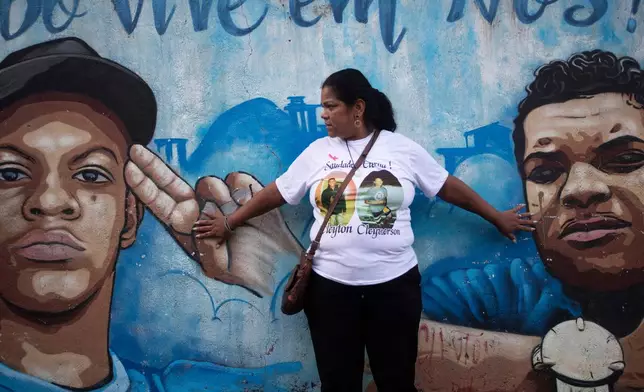 Nadia dos Santos touches a mural honoring her sons, Cleyverson dos Santos Bravo, left, and Cleyton dos Santos Bravo, right, who were killed by police, outside the home where she lived with one of her sons in the Morro da Criança favela in Rio de Janeiro, Thursday, June 4, 2026. (AP Photo/Bruna Prado)
