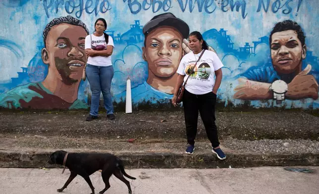 Glaucia dos Santos, left, and her sister Nadia dos Santos stand by a mural honoring their late sons who were killed by police, in the Morro da Criança favela in Rio de Janeiro, Thursday, June 4, 2026. Nadia's two sons are Cleyton dos Santos Bravo, right, and Cleyverson dos Santos Bravo, center. Glaucia's son is Fabricio dos Santos, left. (AP Photo/Bruna Prado)