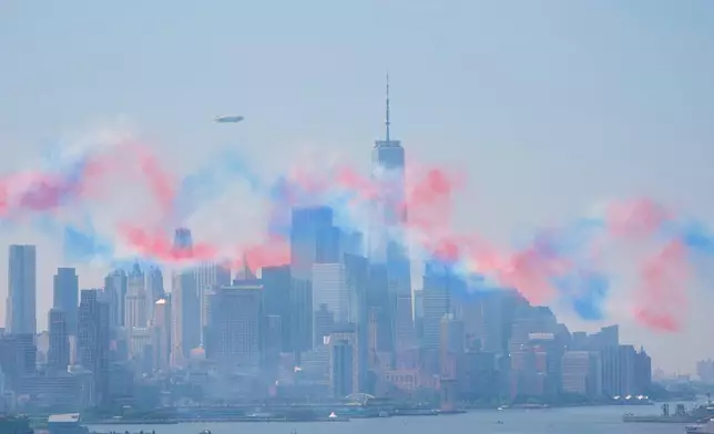 A red, white and blue haze hangs over the Manhattan skyline after military planes perform a flyover of the Hudson River, as seen from Weehawken, N.J., Saturday, July 4, 2026. (AP Photo/Seth Wenig)