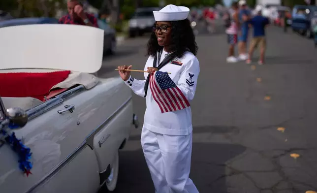 Navy sailor Mykalya Jones dances with a flag as she waits for the start of an Independence Day parade Saturday, July 4, 2026, in Coronado, Calif. (AP Photo/Gregory Bull)