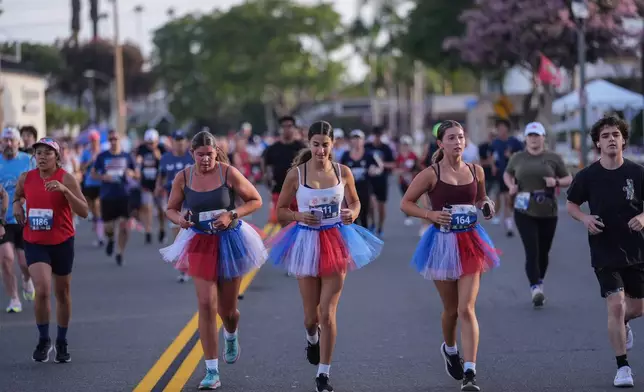Runners in patriotic-colored tutus participate in a run on Independence Day in Huntington Beach, Calif., Saturday, July 4, 2026. (AP Photo/Jae C. Hong)
