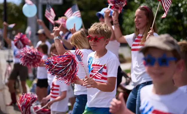 People wave flags during an Independence Day parade Saturday, July 4, 2026, in Coronado, Calif. (AP Photo/Gregory Bull)