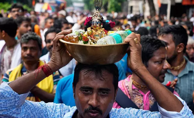 A Hindu devotee carries Hindu god Krishna on his head as he joins the Rath Yatra, or chariot festival, carrying the Hindu deities of Jagannath, Balaram and Subhadra, in Kolkata, India, Thursday, July 16, 2026. (AP Photo/Bikas Das)