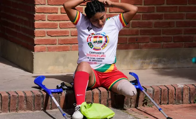 A woman fixes her hair before playing during a women's amputee soccer clinic in Santa Cruz, Bolivia, Friday, July 17, 2026. (AP Photo/Juan Karita)