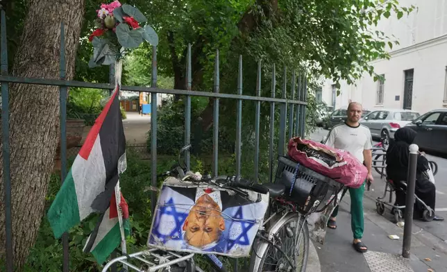 A man walks past a bicycle displaying a Palestinian flag and a photograph depicting Israeli Prime Minister Benjamin Netanyahu as Nazi dictator Adolf Hitler outside the Grand Mosque of Paris as it celebrates its 100th anniversary, Friday, July 17, 2026. (AP Photo/Michel Euler)