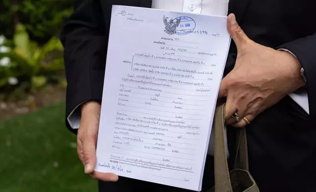 A Thai lawyer holds legal documents for a case filed by former sailors of the Thailand-flagged ship, the Mayuree Naree, outside the Central Labour Court in Bangkok, Thailand on Friday, July 10, 2026. (AP Photo/Anton L. Delgado)