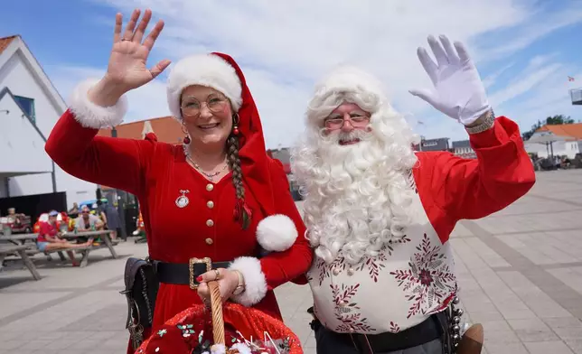 A Santa Claus and Christmas elve performer wave into the camera during the annual World Santa Claus Congress, a colorful midsummer tradition, in Aalborg, Denmark, Wednesday July 8, 2026. (AP Photo/James Brooks)