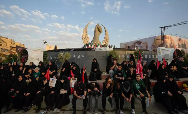 Mourners wait in Islamic Revolution Square for the funeral procession of the slain Iranian Supreme Leader Ayatollah Ali Khamenei beneath a monument depicting Khamenei's clenched fist in Tehran, Iran, Monday, July 6, 2026. (AP Photo/Vahid Salemi)