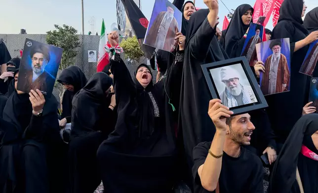 Mourners hold a portrait of Iran's new Supreme Leader, Mojtaba Khamenei, left, and portraits of the slain Iranian Supreme Leader Ayatollah Ali Khamenei while waiting in Islamic Revolution Square for his funeral procession in Tehran, Iran, Monday, July 6, 2026. (AP Photo/Altaf Qadri)