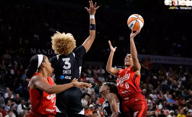 Indiana Fever guard Kelsey Mitchell (0) shoots over Las Vegas Aces guard Jackie Young (0) as forward NaLyssa Smith (3) defends during the first half of an WNBA basketball game Sunday, July 12, 2026, in Las Vegas. Indiana Fever forward Monique Billings is at left. (Steve Marcus/Las Vegas Sun via AP)