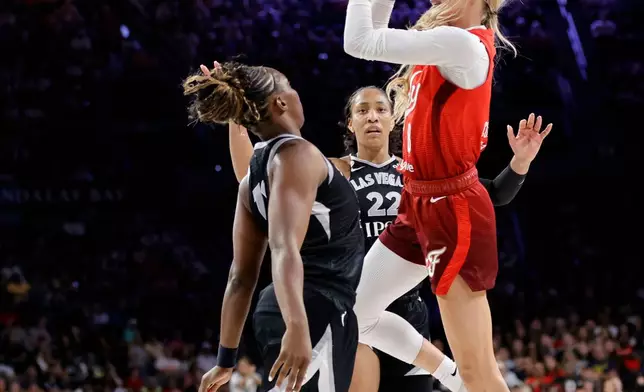 Indiana Fever guard Sophie Cunningham (8) shoots over Las Vegas Aces guard Chelsea Gray (12) as center A'ja Wilson (22) looks on during the first half of an WNBA basketball game Sunday, July 12, 2026, in Las Vegas. (Steve Marcus/Las Vegas Sun via AP)