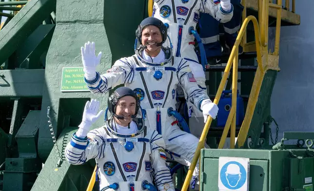 Expedition 75 Roscosmos cosmonaut Anna Kikina, top, NASA astronaut Anil Menon, middle, and Roscosmos cosmonaut Pyotr Dubrov, bottom, wave farewell prior to boarding the Soyuz MS-29 spacecraft for launch, Tuesday, July 14, 2026 at the Baikonur Cosmodrome in Kazakhstan. (Bill Ingalls/NASA via AP)