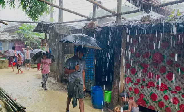People walk through heavy rain at a Rohingya refugee camp in Cox's Bazar, Bangladesh, Tuesday, July 7, 2026. (AP Photo/Shamimul Islam Faisal)