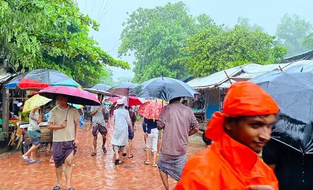 People walk through rain at a Rohingya refugee camp in Cox's Bazar, Bangladesh, Tuesday, July 7, 2026. (AP Photo/Shamimul Islam Faisal)
