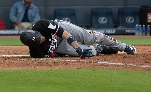 Minnesota Twins' Victor Caratini reacts after fouling a pitch from Cleveland Guardians starting pitcher Slade Cecconi off his leg during the fifth inning of a baseball game, Wednesday, July 22, 2026, in Cleveland. (AP Photo/Phil Long)