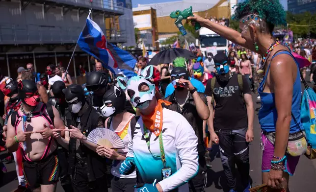 Participants with dog masks attend the Pride March in Berlin, Germany, Saturday, July 25, 2026. (AP Photo/Markus Schreiber)