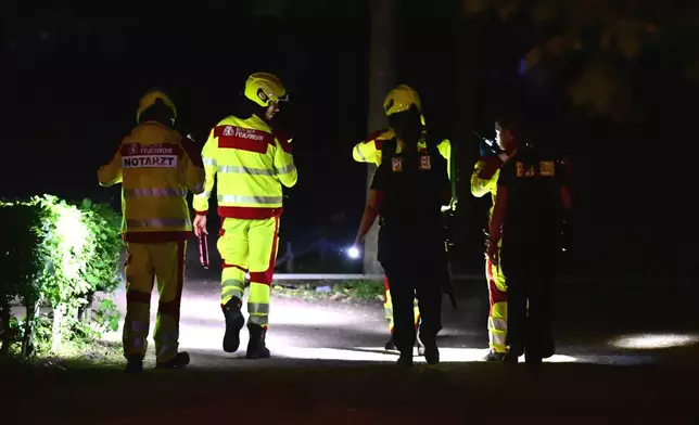 Emergency personnel use flashlights following the cancellation of Christopher Street Day in the Tiergarten area of Berlin on Saturday, July 25, 2026. (Fabian Sommer/dpa via AP)