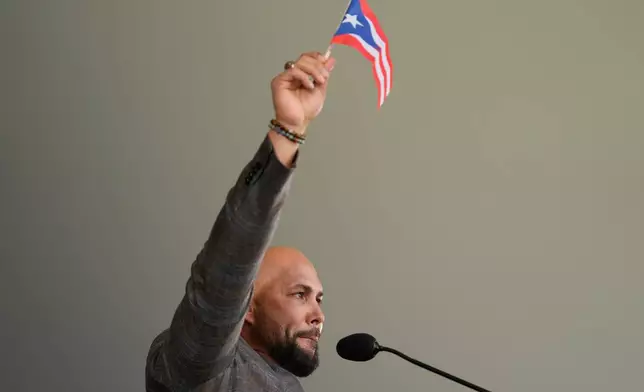 Carlos Beltran waves a Puerto Rican flag while speaking during the Baseball Hall of Fame induction ceremony in Cooperstown, N.Y., Sunday, July 26, 2026. (AP Photo/Seth Wenig)