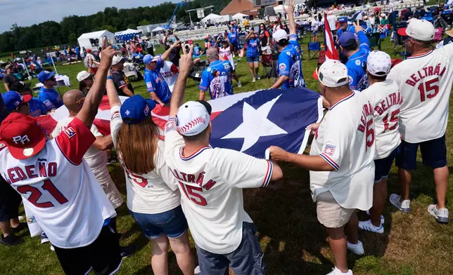 Puerto Rico and Carlos Beltran supporters pose for pictures with a Puerto Rican flag before the start of the Baseball Hall of Fame induction ceremony in Cooperstown, N.Y., Sunday, July 26, 2026. (AP Photo/Seth Wenig)