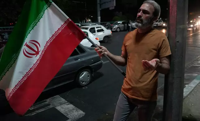 A demonstrator prays as he holds an Iranian flag in a pro-government gathering at a square in Tehran, Iran, Tuesday, July 28, 2026. (AP Photo/Vahid Salemi)
