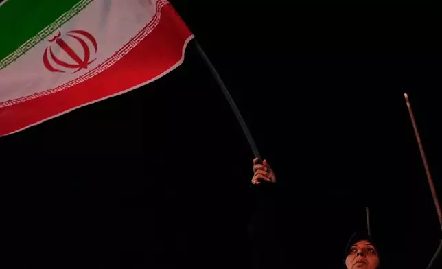 An Iranian pro-government demonstrator waves her country's flag in a gathering at a square in Tehran, Iran, Tuesday, July 28, 2026. (AP Photo/Vahid Salemi)