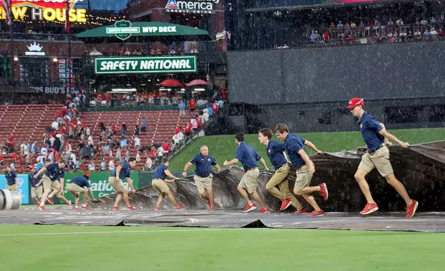 Members of the St. Louis Cardinals grounds crew tarp the field during a rain delay at the top of the fourth inning of a baseball game against the Atlanta Braves Friday, July 10, 2026, in St. Louis. (AP Photo/Scott Kane)