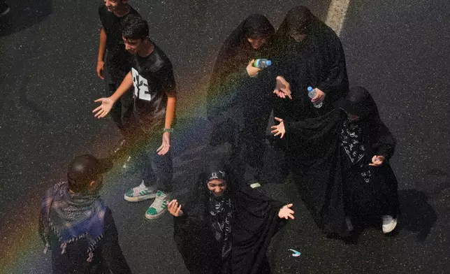 Mourners cool off under a spray of water as they walk to the Imam Khomeini Mosalla Grand Mosque during the dayslong funeral ceremonies for the late Iranian Supreme Leader Ayatollah Ali Khamenei in Tehran, Iran, Saturday, July 4, 2026. (AP Photo/Vahid Salemi)