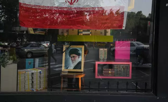 A portrait of slain Iranian Supreme Leader Ayatollah Ali Khamenei and an Iranian flag are displayed in the window of a bookstore ahead of Khamenei's funeral ceremonies, in Tehran, Iran, Thursday, July 2, 2026. (AP Photo/Vahid Salemi)
