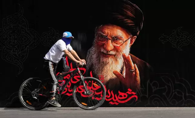 A man rides a bicycle past a portrait of slain Iranian Supreme Leader Ayatollah Ali Khamenei ahead of his dayslong funeral ceremonies in Tehran, Iran, Friday, July 3, 2026. (AP Photo/Vahid Salemi)