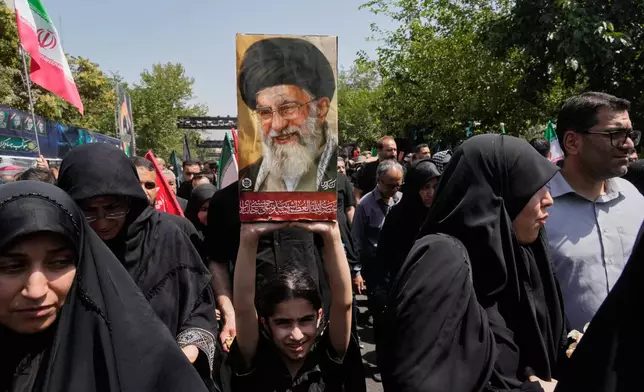 A girl holds a portrait of the late Iranian Supreme Leader Ayatollah Ali Khamenei as she walks to the Imam Khomeini Mosalla Grand Mosque during his dayslong funeral ceremonies in Tehran, Iran, Saturday, July 4, 2026. (AP Photo/Vahid Salemi)