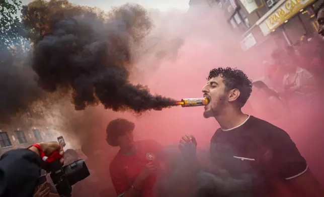 A Morocco fan holds a flare in his mouth after the team lost the World Cup quarterfinal soccer match between France and Morocco, Thursday, July 9, 2026, in the Queens borough of New York. (AP Photo/Ryan Murphy)
