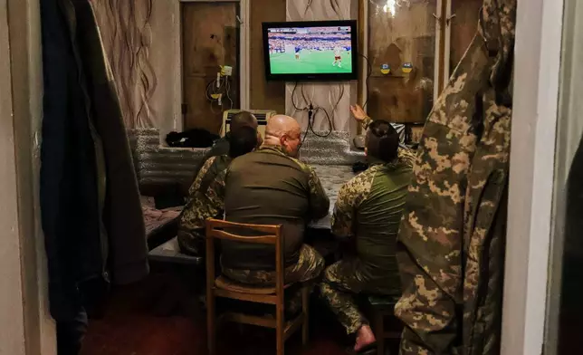 In this photo provided by Ukraine's 65th Mechanized Brigade press service, soldiers react as they watch a broadcast of the World Cup semifinal soccer match between France and Spain after after a mission on the frontline in the Zaporizhzhia region, Ukraine, Tuesday, July 14, 2026. (Andriy Andriyenko/Ukraine's 65th Mechanized Brigade via AP)