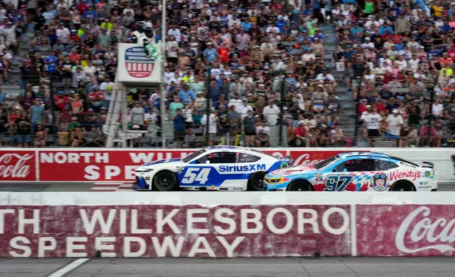 Ty Gibbs (54) passes Shane van Gisbergen (97) to win the first segment of a NASCAR Cup Series auto race in North Wilkesboro, N.C., Sunday, July 19, 2026. (AP Photo/Chuck Burton)