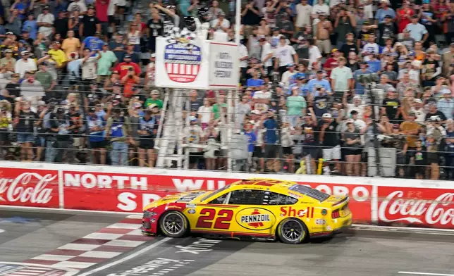 Joey Logano (22) takes th checkered flag to win a NASCAR Cup Series auto race in North Wilkesboro, N.C., Sunday, July 19, 2026. (AP Photo/Chuck Burton)