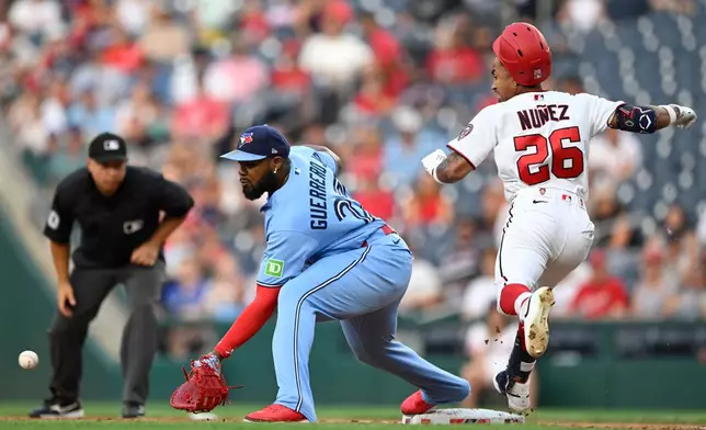 Washington Nationals' Nasim Nuñez (26) beats out a throw to Toronto Blue Jays first baseman Vladimir Guerrero Jr., center, during the second inning of a baseball game, Monday, July 27, 2026, in Washington. (AP Photo/John McDonnell)