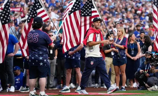 United States men's national soccer team's Christian Pulisic walks to the field before head coach Mauricio Pochettino threw out the ceremonial first pitch before a baseball game between the Seattle Mariners and the Toronto Blue Jays, Friday, July 3, 2026, in Seattle. (AP Photo/Lindsey Wasson)