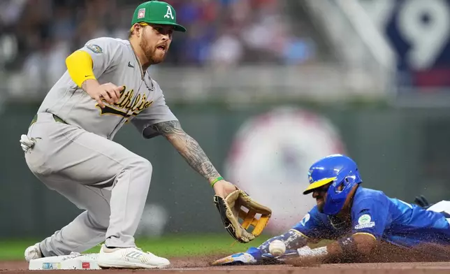 Athletics third baseman Tommy White, left, attempts to catch the ball while Minnesota Twins' Royce Lewis slides safely into third base during the fourth inning of a baseball game, Friday, July 24, 2026, in Minneapolis. (AP Photo/Ellen Schmidt)