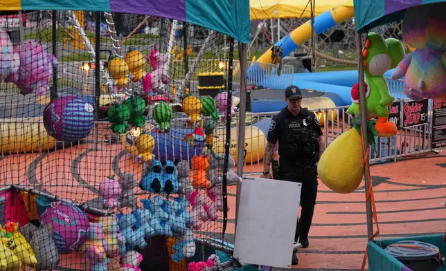A Seattle Police officer walks through tents with colorful toys at the scene of a shooting at Seattle Center during the Bite of Seattle food festival Sunday, July 26, 2026, in Seattle. (AP Photo/Lindsey Wasson)