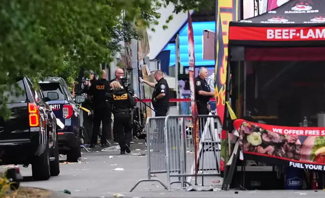 A crime scene photographer arrives as law enforcement examines the scene following a shooting at Seattle Center during the Bite of Seattle food festival Sunday, July 26, 2026, in Seattle. (AP Photo/Lindsey Wasson)