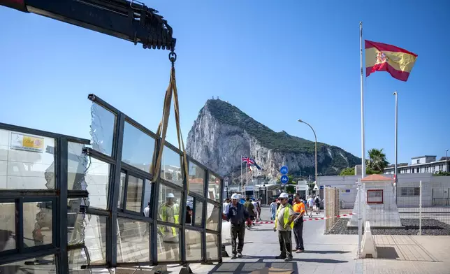 Against the backdrop of the Rock of Gibraltar, workers dismantle a Spanish border checkpoint that separated the disputed British overseas territory from Spain in La Línea de la Concepción, Spain, Monday, July 6, 2026. (AP Photo/Marcos Moreno)
