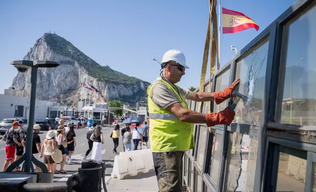 Against the backdrop of the Rock of Gibraltar, workers dismantle a Spanish border checkpoint that separated the disputed British overseas territory from Spain in La Línea de la Concepción, Spain, Monday, July 6, 2026. (AP Photo/Marcos Moreno)
