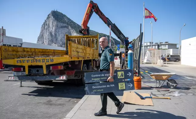 A Spanish Guardia Civil officer holds a sign during the dismantling of a border checkpoint that separated Spain from the disputed British overseas territory of Gibraltar in La Línea de la Concepción, Spain, Monday, July 6, 2026. (AP Photo/Marcos Moreno)