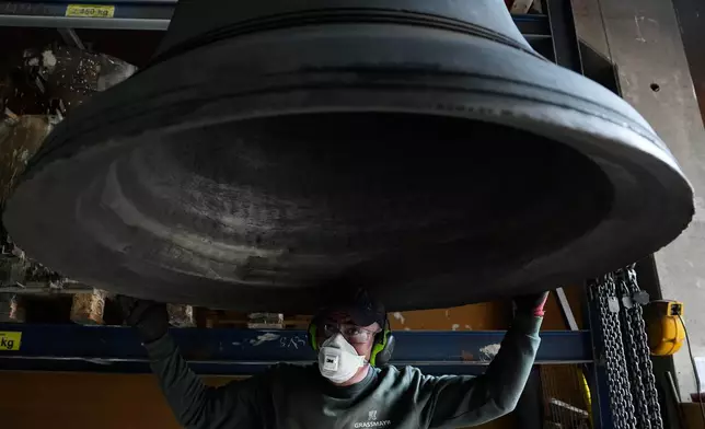 An employee inspects a bell at the 400-year-old family-owned bell foundry Grassmayr in Innsbruck, Austria, Friday, July 17, 2026. (AP Photo/Matthias Schrader)