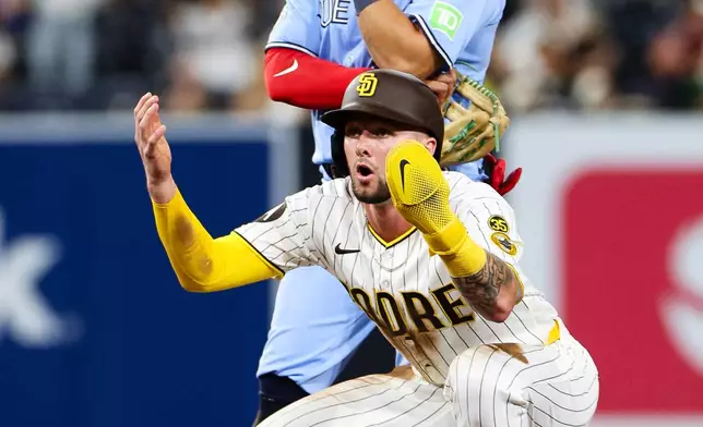 San Diego Padres' Jackson Merrill, bottom, reacts after the team challenged the out call on an attempted steal as Toronto Blue Jays' Luis Urías looks on in the eighth inning of a baseball game Saturday, July 11, 2026, in San Diego. (AP Photo/Derrick Tuskan)