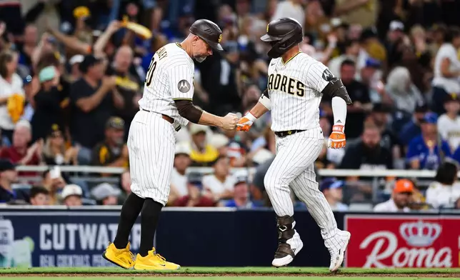 San Diego Padres' Ty France, right, is congratulated by third base coach Bob Henley, left, as he rounds the bag after hitting a solo home run against the Toronto Blue Jays in the sixth inning of a baseball game Saturday, July 11, 2026, in San Diego. (AP Photo/Derrick Tuskan)