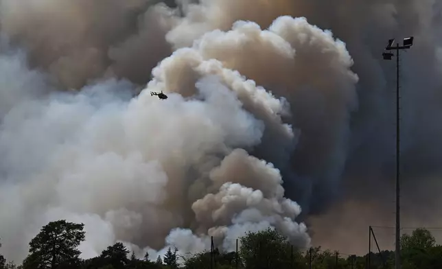 A fire fighting helicopter in action as wildfires are seen in the Fontainebleau forest region, about 60 kilometers (37 miles) south of Paris, France, Monday, July 13, 2026. (AP Photo/Emma Da Silva)
