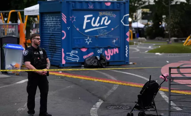 A police officer stands at a closed off area after a shooting at Seattle Center during the Bite of Seattle food festival Sunday, July 26, 2026, in Seattle, Wash. (AP Photo/Lindsey Wasson)